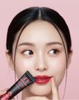 A model touching the Morichae Lip Tattoo Tint Pack to her lips, highlighting smooth texture and natural color glow after tinting.
