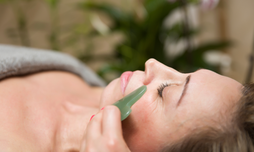 Close-up of a woman receiving a gua sha facial massage with a beauty tool